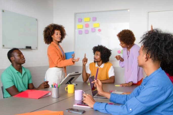 A group of employees in a conference room working on a whiteboard activity